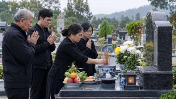 Người thân mặc trang phục trang nghiêm, thắp nhang và dâng lễ vật tại mộ trong ngày cúng thất đầu tiên.